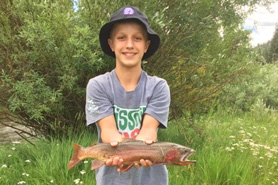 Boy holding rainbow trout caught at the Riverbend Resort Cabins and RV park near the South Fork Colorado area. Catch Your 1st or 1000th Trout. Fishing Steps away from Your Lodging.