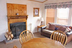 Cabin living room with fireplace at Riverbend Resort Cabins and RV Park in the South Fork Area of Colorado. Modern Log Cabins. Kitchen Equipped with Refrigerator, Range and Coffeemaker.