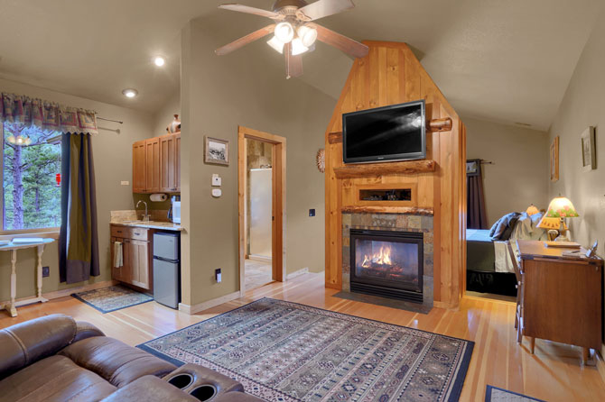 Interior view of cabin with fireplace, kitchenette, roku tv, desk, couch and bed Pikes Peak Guest Cabin at Rocky Mountain Lodge in Cascade, Colorado.