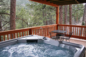 Hot tub and small table with chairs on outdoor covered deck with mountain views at Rocky Mountain Resorts in Estes Park, Colorado