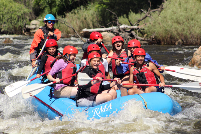 A group in a raft white water rafting on the Cache La Poudre River with a raft rented from Rocky Mountain Adventures, Colorado. Rafting is wild, scenic, and perfect for families.