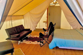 Inside view of Glamping Estate King Deluxe Canvas Camper Cabin Tent at Rustic Rook Resort located near the Great Sand Dunes in Alamosa, Colorado.. Luxurious Linens and Towels. Hot Farm to Table Breakfast. Lanterns and USB Charging Station. Dog Friendly.