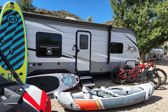 RV trailer with recreational equipment at Rimrock Adventures RV Park in Naturita, Colorado.