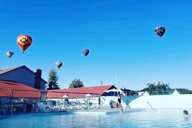 Hot air balloons floating above hot springs pool during Annual Colorfest Balloon Rally at Healing Waters Resort and Spa near Durango in Pagosa Springs, Colorado