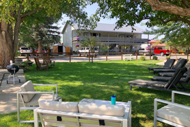 Large shaded seating area in gardens with chaise lounge chairs, couches and bbq grill in front of Healing Waters Resort and Spa near Durango in Pagosa Springs, Colorado.