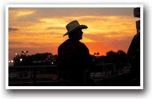 Cowboy stands with orange sunset at the Colorado State Fair in Pueblo, Colorado