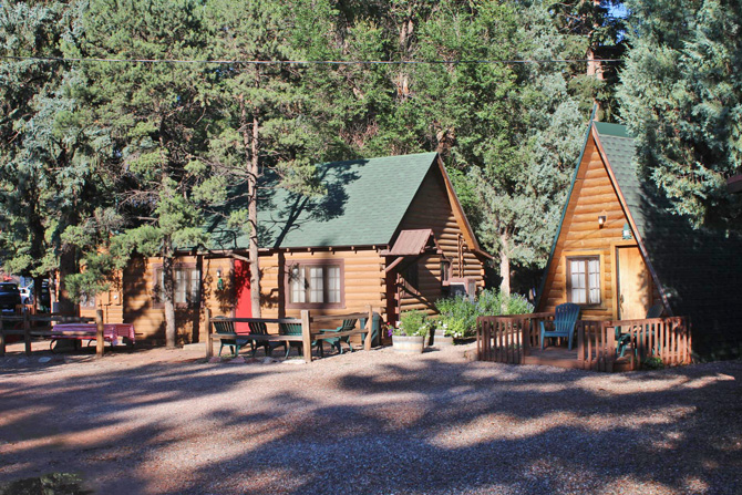 A-frame and Log Cabins nestled in pine trees at Timber Lodge Rustic Log Cabins in Colorado Springs, Colorado
