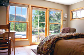 Inside view of lodge room with amazing views of mountains through large windows and windowed door to patio at Roadhouse Lodge and Vacation Home Rentals in Twin Lakes, Colorado.