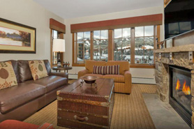 Indoor view of luxurious and spacious living room with stone fireplace, large hd tv, comfortable furnishings, and amazing view of the mountains at Beaver Creek and Vail Vacation Rentals in Colorado.